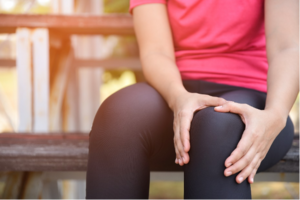 A person sitting on a bench holding her knee